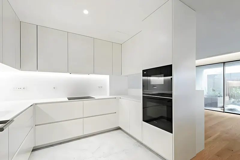 Cocina blanca abierta al salón con horno en columna — obra en Fuengirola