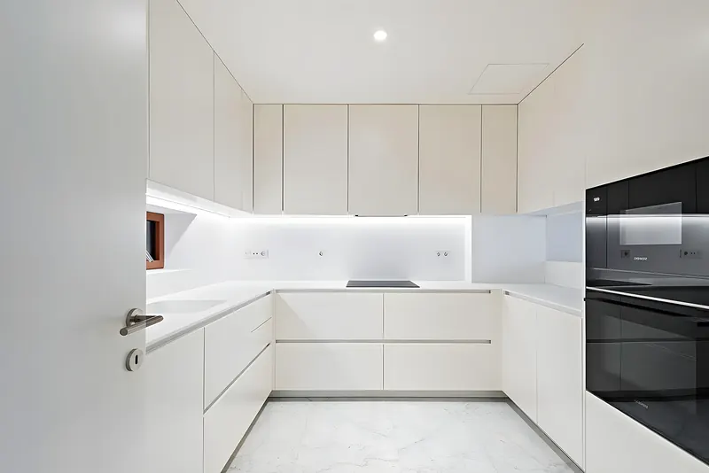 Frente de la misma cocina blanca con luz bajo mueble — Fuengirola
